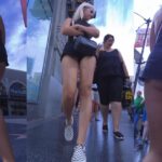 Slim Blonde in Black Shorts Walking Down the Street