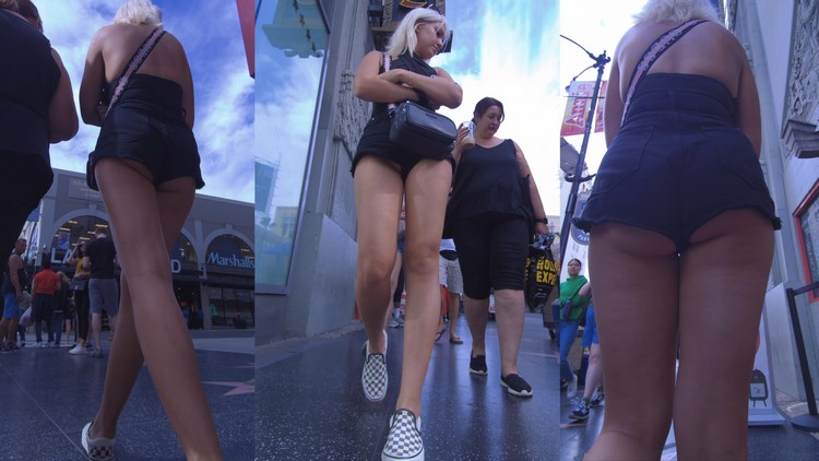 Slim Blonde in Black Shorts Walking Down the Street